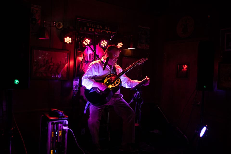 A picture of a man playing music with guitar in disco light